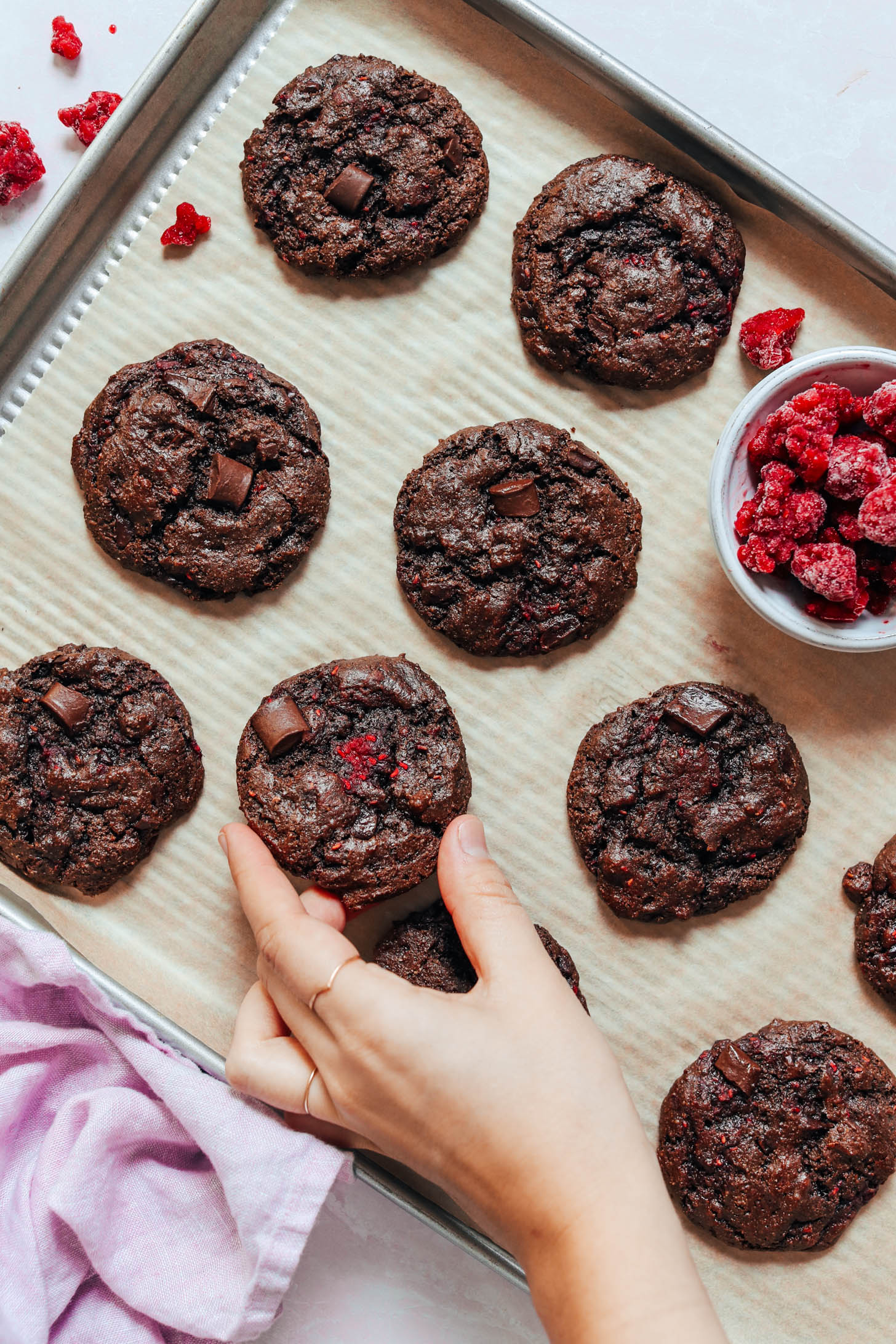 Picking up a gluten-free chocolate raspberry cookie from a baking sheet